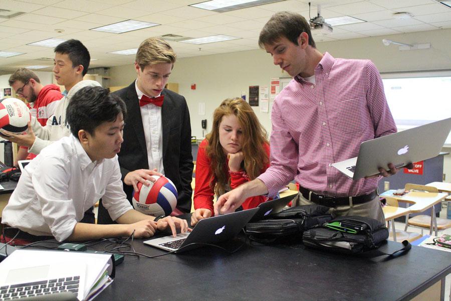Mr. Tanner Stevens aids students with a physics lab. 