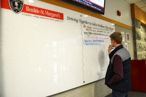 Senior Parker Breza adds problems that he believes matters to the whiteboard recently added to the lobby. 