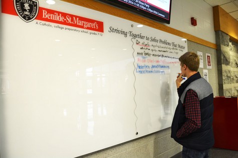 Senior Parker Breza adds problems that he believes matters to the whiteboard recently added to the lobby. 