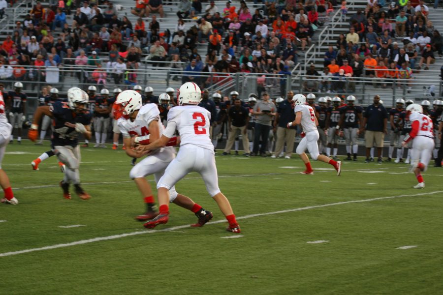 Senior quarterback Will Whitmore hands the ball off to senior running back Alex Houlihan, in the Red Knights' first road game of the season against Robbinsdale Cooper.