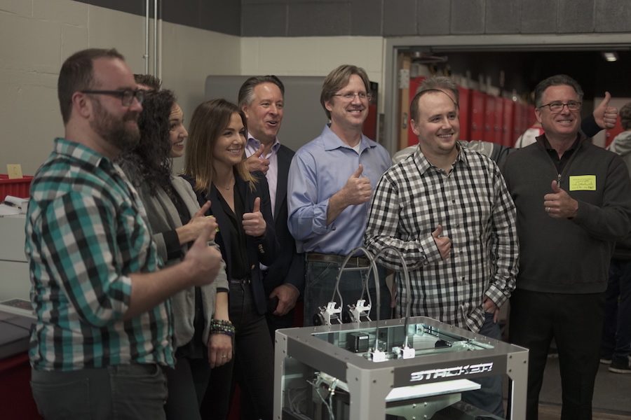 The teachers of the BSM engineering department, the men of Stacker, and the donors who made the printer possible all stand around the new 3D Printer.