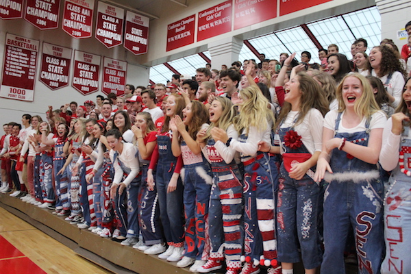 Senior girls cheer at a pep fest in their overalls.