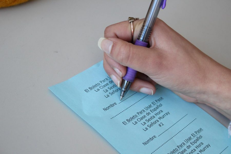 A student signs a Spanish class hall pass which will result in a loss of extra credit. Some teachers have taken to keeping students in class through the threat of withholding extra credit.