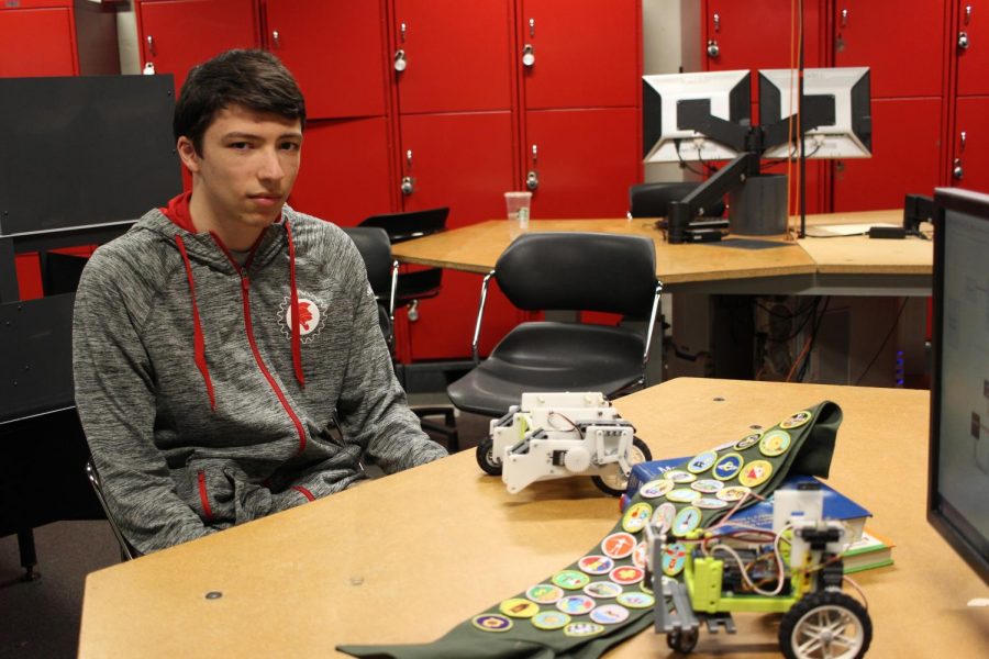 Brady Solomon shows off his robot and merit badges.