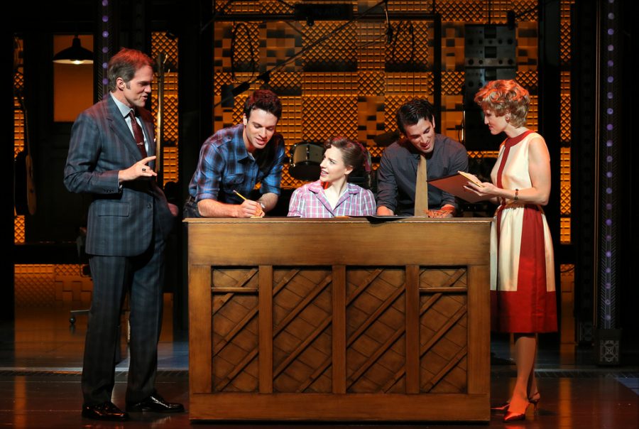 The cast of Beautiful: The Carole King Musical gathers around a piano during a performance