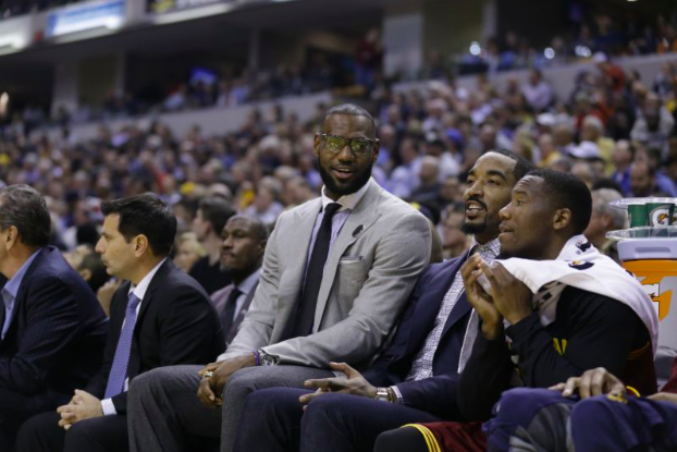 Lebron James (left) talking to J.R. Smith (center), whilst the two players watch a game from the sidelines.