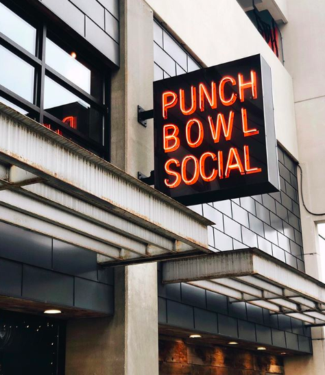 The sign off Punch Bowl Social hangs on the side of the restaurant