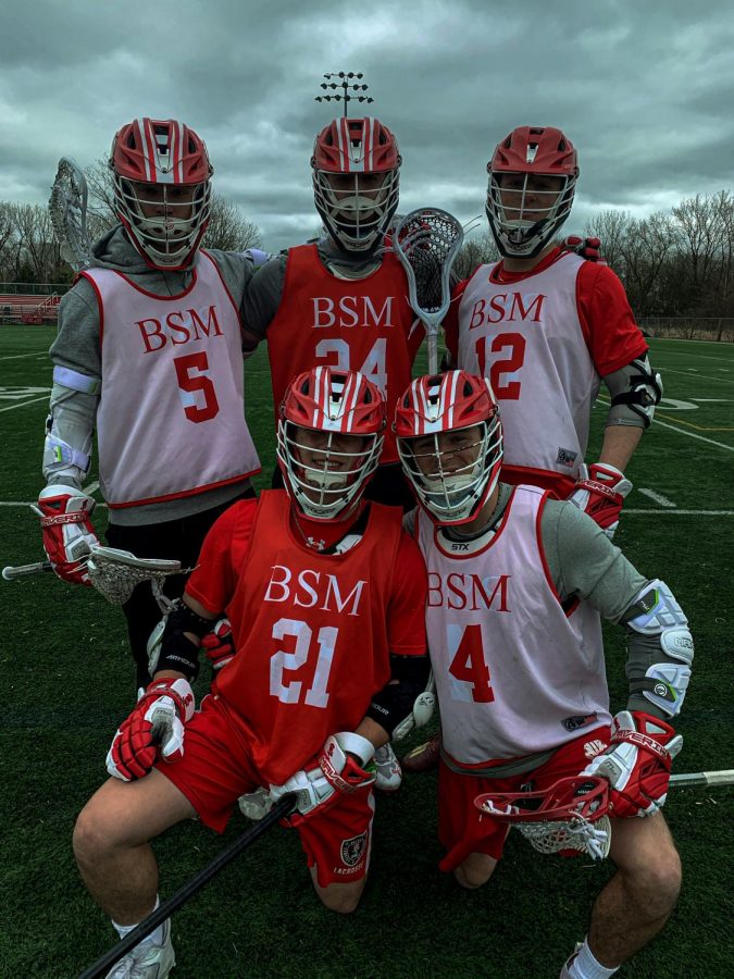 Boys lacrosse players pose on the field midway through preparation for their first game of the 2021 season. 