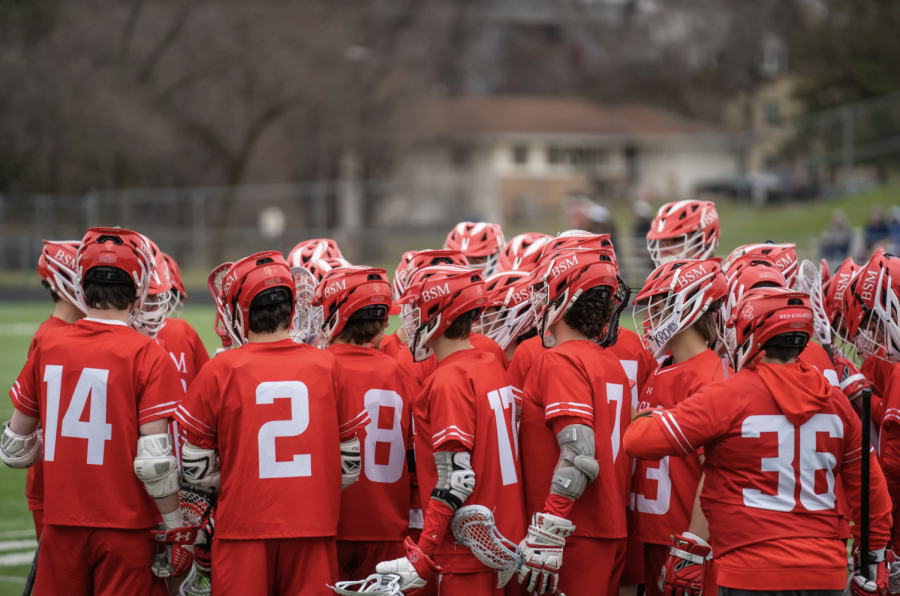 BSMs boys lacrosse team discusses game strategies in a team huddle.