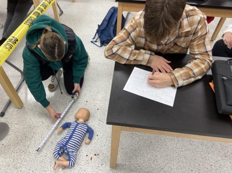 Forensics students measuring and sketching a crime scene in class.