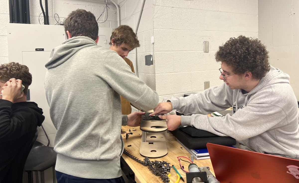 Several engineering students work collaboratively on a robot they designed.