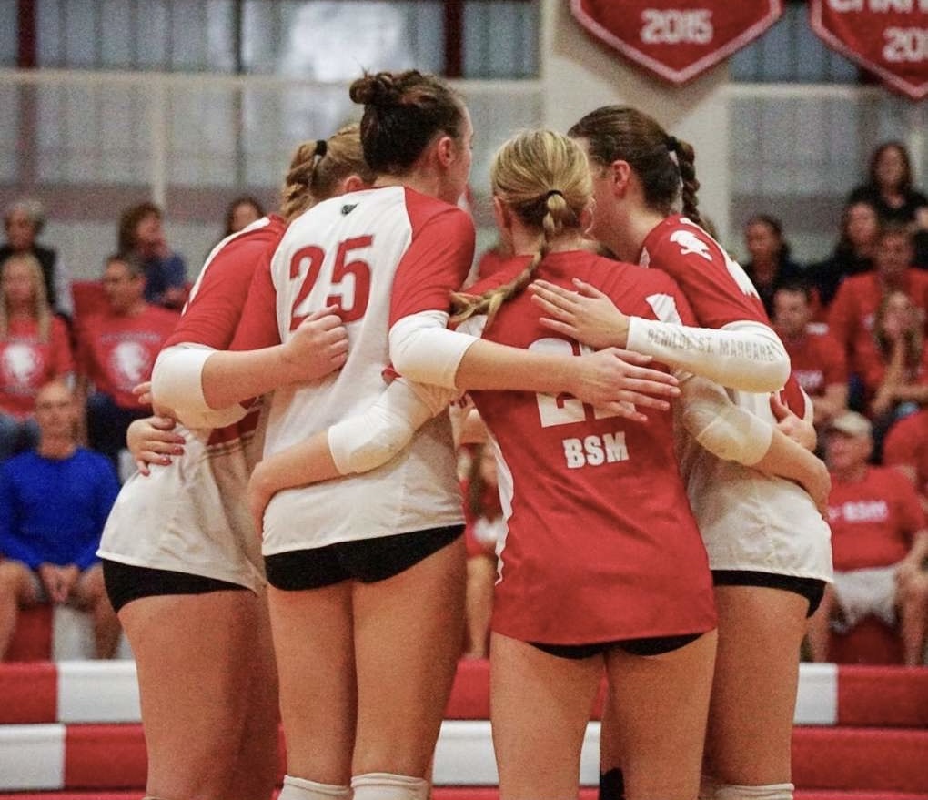 BSM girls' volleyball in a huddle planning their next play at their home match.